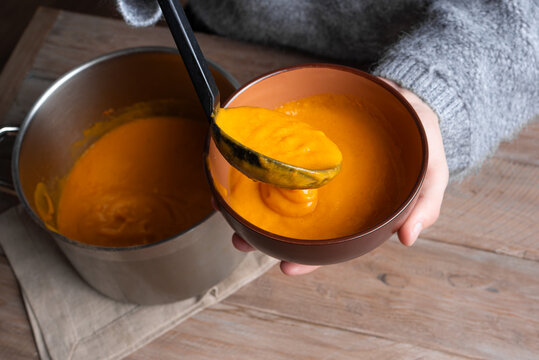 Person's hands ladling soup into bowl