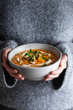 Bowl of pumpkin soup in woman hands