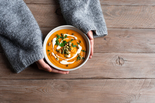 Bowl of pumpkin soup in woman hands