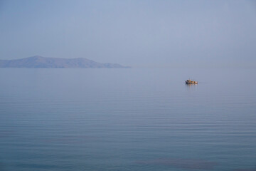 Fototapeta premium Small fishing boat on calm sea off Lotos Beach, Syros, Greece 