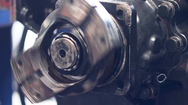 Close up side view of spinning industrial transmission output flange in workshop.