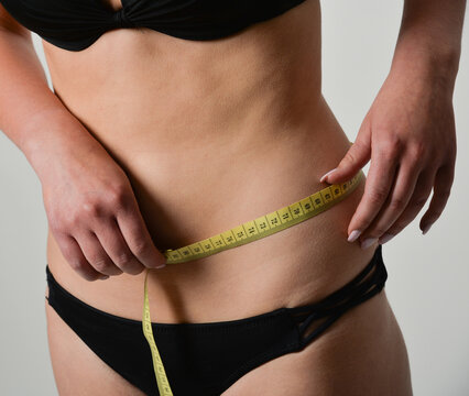 Frau misst den H&uuml;ft- und Ges&auml;&szlig;umfang mit einem Ma&szlig;band. Fitness, Abnehmen, K&ouml;rperm