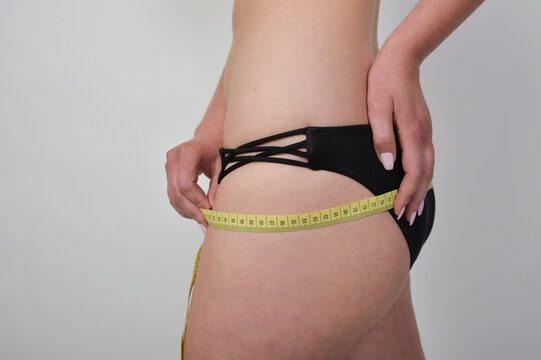 Frau misst den H&uuml;ft- und Ges&auml;&szlig;umfang mit einem Ma&szlig;band. Fitness, Abnehmen, K&ouml;rperm