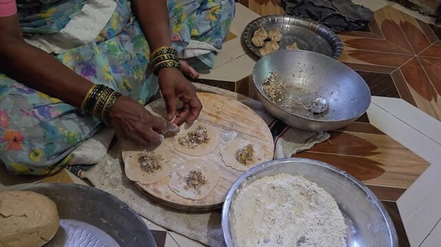 The intentional rhythm of hand pleating that exceeds basic culinary preparation carefully folds sweet jaggery coconut filling into raw ukdiche modak wrappers, embodying generations of mindful devotion
