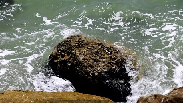 video al rallentatore di acqua di mare che si infrange sugli scogli lungo la costa di giorno