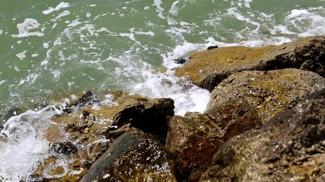 video al rallentatore di acqua di mare che si infrange sugli scogli lungo la costa di giorno