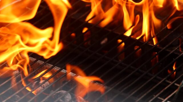 video dettagliato di fiamme che si muovono e di bronze che ardono in una griglia durante la preparazione di un barbecue