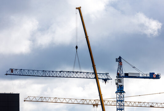 View of construction cranes operating against a cloudy sky in Vilnius, Vilnius County, Lithuania.