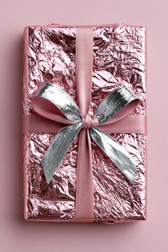A beautifully wrapped gift in shiny pink foil with a silver ribbon.