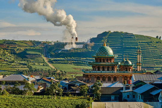 View of the mosque in Dieng Kulon surrounded by terraced agricultural hills and a geothermal power plant in Batur, Central Java, Indonesia.