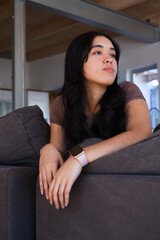 Obraz premium African American woman reclining on gray sectional couch in living room wearing pink smartwatch