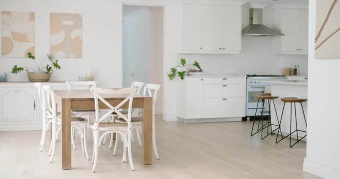 Camera is panning right, showing wood dining table and four white chairs, revealing kitchen