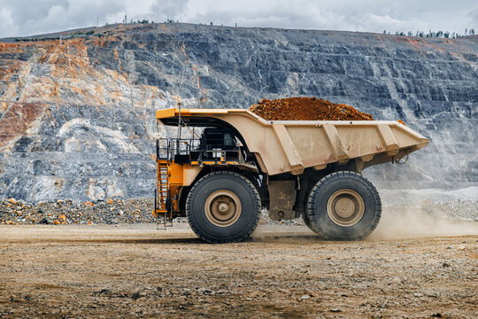 Large haul truck driving along bench in open pit mine iron and gold ore