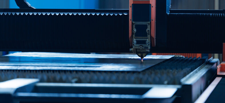 Cnc laser cutter cutting metal sheet in industrial workshop
