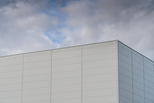 View of a modern building facade with white panels against a cloudy sky in Poland.