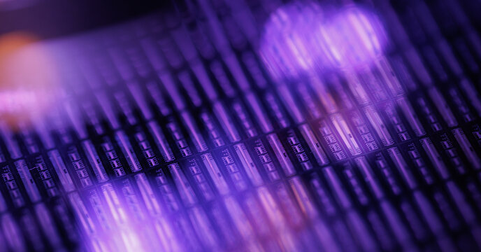 Shallow depth silicon microchip wafer with purple neon glow for technology background