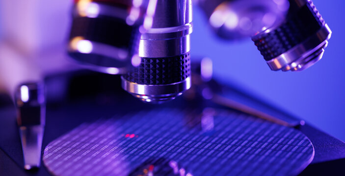 Microscopic view of silicon wafer under microscope objective with purple lighting for technology wallpaper and laboratory background