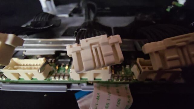 Extreme close-up macro shot of two white wire connector plugs hovering above their sockets on an internal circuit board of a disassembled electronic device.