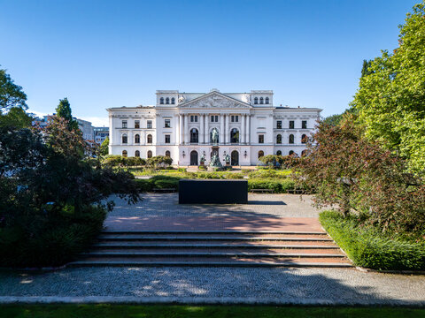 View of the historic Altona City Hall with its neoclassical facade, lush park, and clear blue sky, Hamburg, Hamburg, Germany.