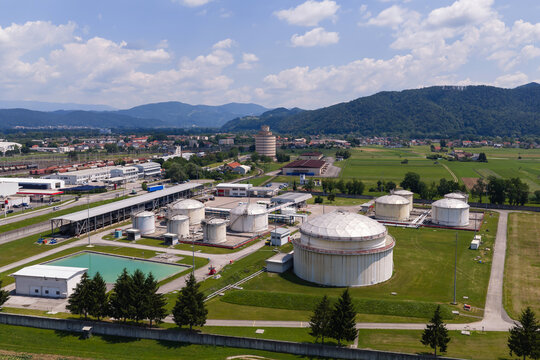 Aerial view of an oil storage facility showing several large tanks and surrounding green areas.