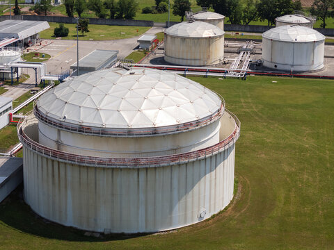 Aerial view shows large oil tanks in a petroleum storage facility located in an industrial area.