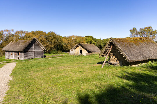 View of Ribe VikingeCenter featuring traditional Viking-style houses with thatched roofs and timber walls set in a grassy field in Ribe, Jutland, Denmark.
