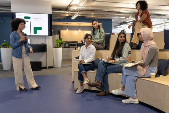 Diverse coworkers listening while presenter speaking with handheld mic at office meeting