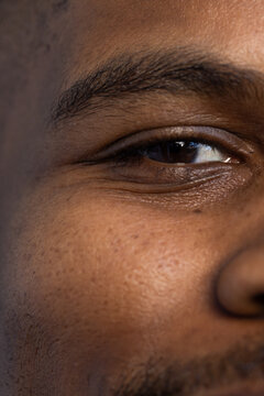 African man holding steady gaze in studio close-up, revealing pores, stubble and eye reflection
