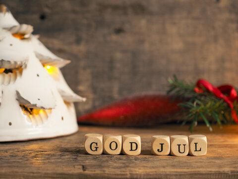 Small wooden blocks with God Jul and white Christmas lantern, rustic wooden background
