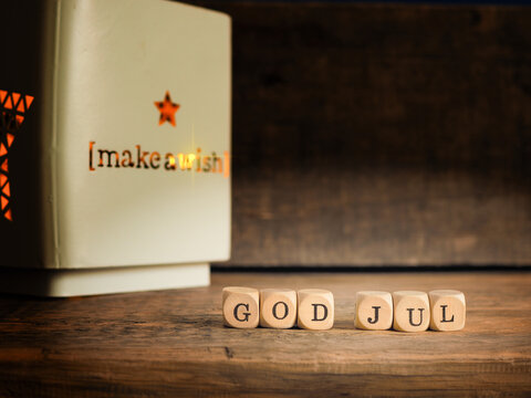 Small wooden blocks with God Jul and white Christmas lantern, rustic wooden background