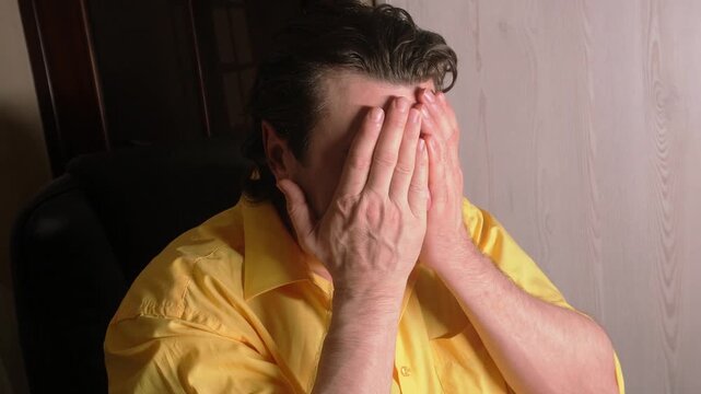 The man is sincerely remorseful. He is upset and covers his face with his hands out of shame.
