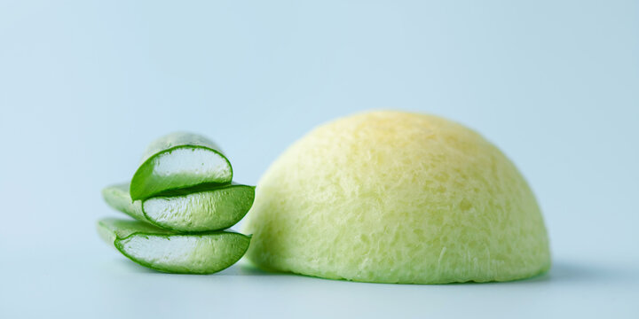 Handmade organic natural soap and aloe vera leaves on a beige background.