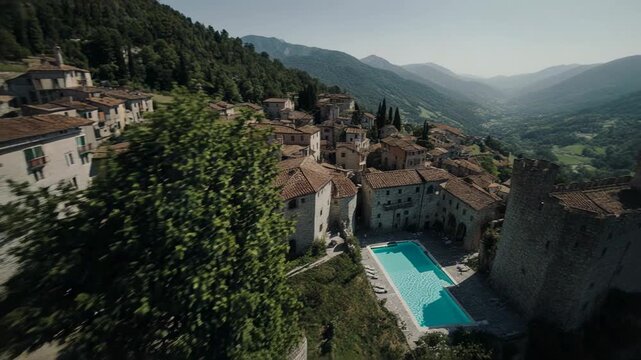 Italian village with pool during golden hour with cinematic drone flyover establishing shot