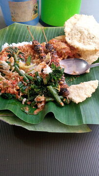  Pecel rice with peanut sauce and Clam satay and gendar crackers is a traditional Indonesian food.