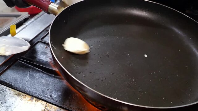 Lobster pieces are cooked in a frying pan with butter over open flames on a kitchen stove before being plated onto a white dish for fine dining service