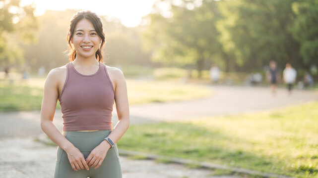 Smiling woman in sportswear standing in a green park after exercise