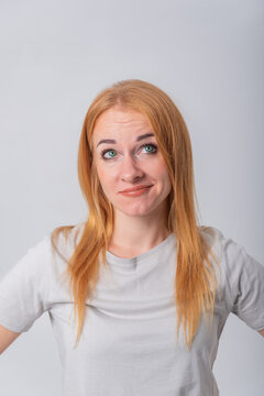 Young woman shrugging with a questioning gaze, showing uncertainty and a need for clarification or answer while looking up with a slightly puzzled face
