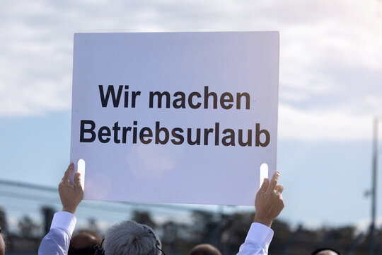(Fotomontage) Ein Schild mit dem Text WIR MACHEN BETRIEBSURLAUB wird in die H&ouml;he gehalten