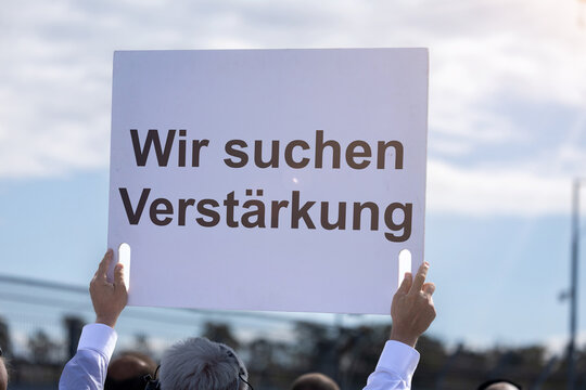 (Fotomontage) Ein Schild mit dem Text WIR SUCHEN VERST&Auml;RKUNG wird in die H&ouml;he gehalten