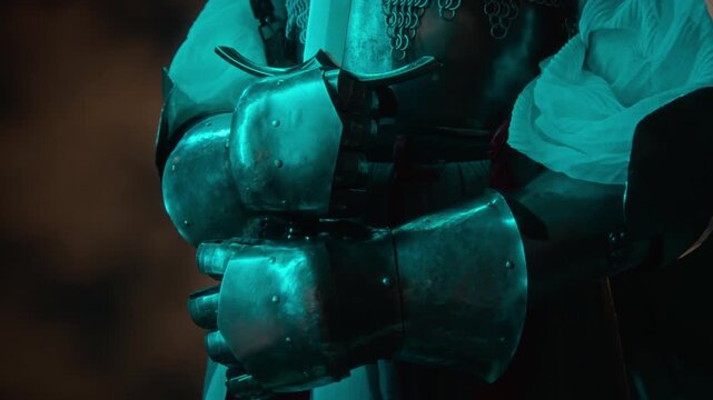 Unknown medieval knight in steel plate gauntlets gripping sword hilt standing ready. Footage suitable for fantasy gaming promo, cinematic trailer, or historical film project