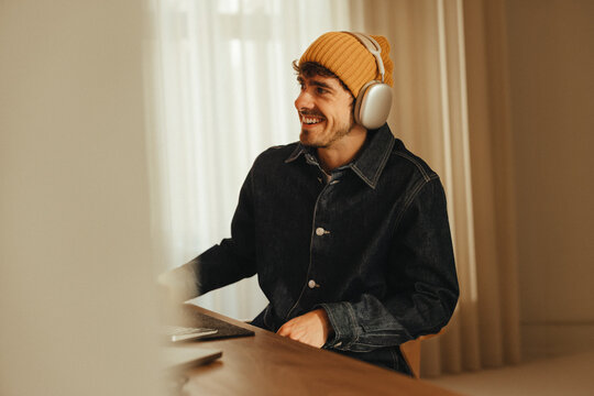 Creative man works at desk with headphones in modern office