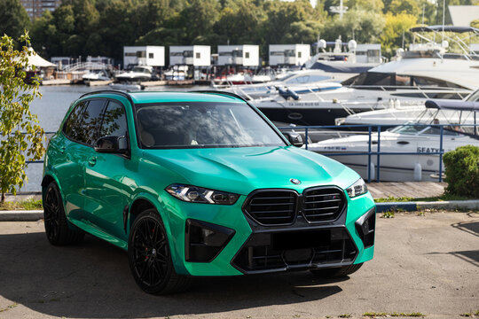 Car Tiffany green BMW X5 parked near luxury yachts and forest background under a clear blue sky. Premium SUV lifestyle photography, vibrant summer atmosphere, modern automotive design