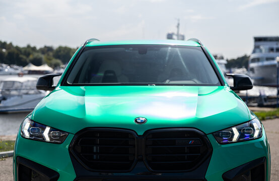 Car Tiffany green BMW X5 parked near luxury yachts and forest background under a clear blue sky. Premium SUV lifestyle photography, vibrant summer atmosphere, modern automotive design