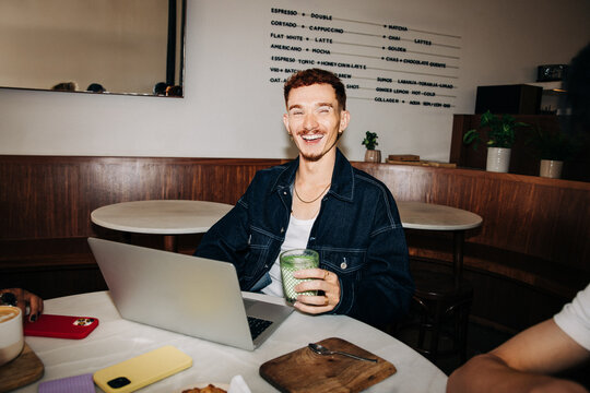 Smiling young man working on laptop in cafe