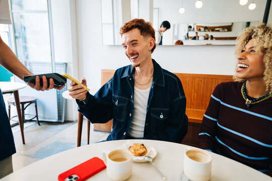 Friends making a contactless payment at a cafe