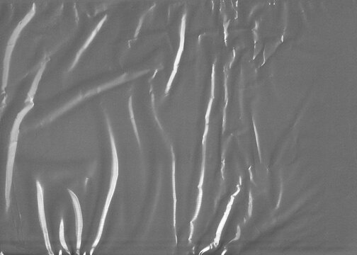 Wrinkled transparent plastic cellophane film covers a full grey background forming a highly textured protective packaging material overlay.