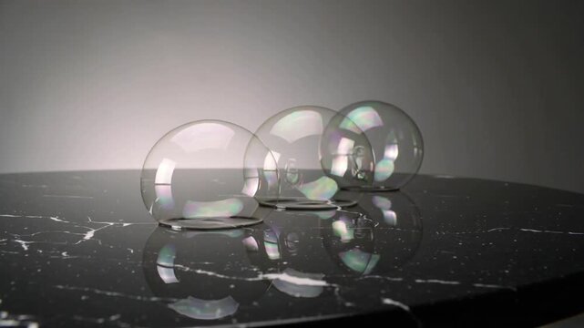 Playing back three soap bubbles shifting right on glossy marble, pinching film bridge reforming