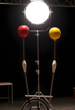 Circus performance and entertainment industry, unicycle with red and yellow balls in a dark studio with professional stage lighting for theatrical arts