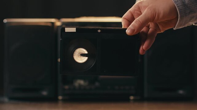 Man holding VHS betacam cassette tape in front of film tape recorder retro vintage close up