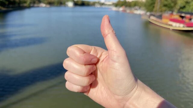 Pitk&auml;silta, Helsinki: Hand Making a Thumbs Up Gesture Over a City Canal View